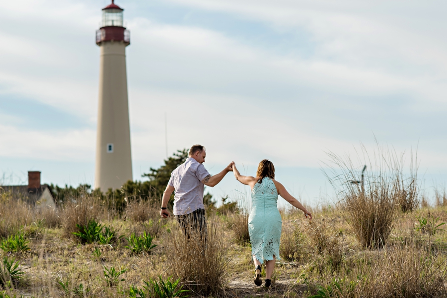 A man helps is fiance up the hill towards the lighthouse in cape may.